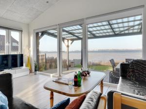 een woonkamer met een tafel en uitzicht op de oceaan bij Holiday Home Käthe - 5m from the sea in Funen by Interhome in Middelfart