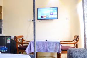 a room with a table and a tv on the wall at Khalisee Homes Studio apartment in Voi