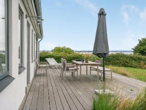 a wooden deck with a table and an umbrella at Holiday Home Sissela - 5m from the sea by Interhome in Ebberup