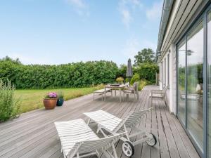 um deque de madeira com cadeiras, uma mesa e um guarda-sol em Holiday Home Sissela - 5m from the sea in Funen by Interhome em Ebberup