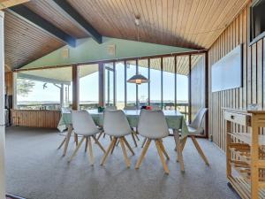 ein Esszimmer mit einem Tisch, Stühlen und Fenstern in der Unterkunft Holiday Home Nnykka - 100m from the sea in Funen by Interhome in Bøjden