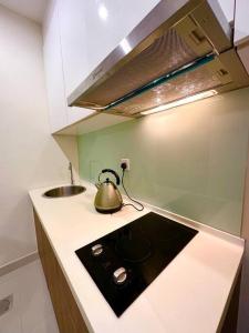 a kitchen with a sink and a tea kettle on a counter at Kuching Kozi Square Apartment in Kuching