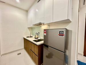 uma cozinha com um frigorífico de aço inoxidável e armários brancos em Kuching Kozi Square Apartment em Kuching