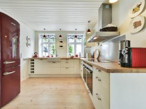 a kitchen with white cabinets and a wooden floor at Holiday Home Gunhilda - 200m from the sea in Funen by Interhome in Spodsbjerg