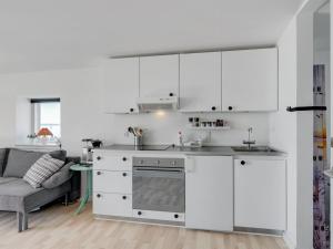a white kitchen with white cabinets and a couch at Apartment Axlan - 50m from the sea in Funen by Interhome in Tranekær