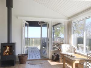 ein Wohnzimmer mit einem Kamin und einer Terrasse in der Unterkunft Holiday Home Bridgette - 100m from the sea in Funen by Interhome in Tranekær
