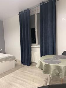 1 dormitorio con cortinas azules, mesa y ventana en Квартира в новому ЖК Svitlo Park Київ, en Kiev