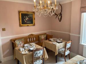 een eetkamer met 2 tafels en een kroonluchter bij Albury House in Cromer