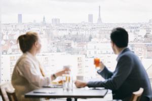 コロンブにあるKOPSTER Hotel Residence Paris Ouest Colombesのドリンクを飲みながらテーブルに座る2名