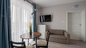 una sala de estar con una mesa y un sofá en Horyzont Apartamenty -Bałtycka2 - SAUNA & FITNESS - ŚNIADANIA, en Kołobrzeg