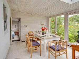 a dining room with a white table and chairs at Holiday Home Gytta - 1km from the sea in Funen by Interhome in Tranekær