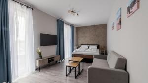 Un dormitorio con una cama, un sofá y un televisor. en Horyzont Apartamenty -Bałtycka2 - SAUNA & FITNESS - ŚNIADANIA, en Kołobrzeg