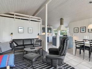 a living room with black furniture and a kitchen at Holiday Home Caia - 375m from the sea in Funen by Interhome in Tranekær