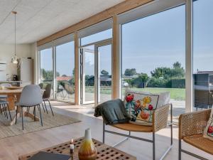 sala de estar con ventanas de cristal, mesa y sillas en Holiday Home Sebbi - 90m from the sea in SE Jutland by Interhome, en Binderup Strand