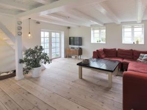 a living room with a red couch and a table at Holiday Home Harre - 300m from the sea in Funen by Interhome in Rudkøbing