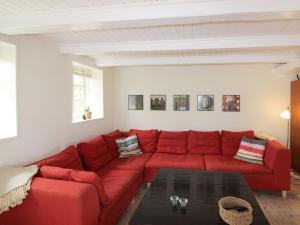 a red couch in a living room with a table at Holiday Home Harre - 300m from the sea in Funen by Interhome in Rudkøbing