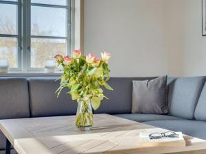 un vase de fleurs sur une table devant un canapé dans l'établissement Holiday Home Nita - 24km from the sea in Western Jutland by Interhome, à Højer