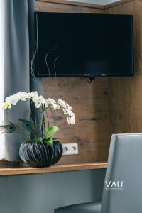 a desk with a television and a vase with flowers at Vau in Stuttgart