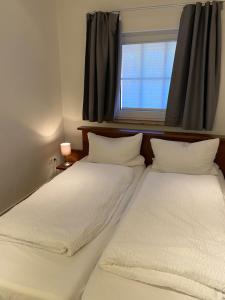 2 camas blancas en una habitación con ventana en Ferienhaus Lammertshörn Bensersiel en Bensersiel
