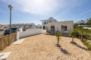 a white house with a street light and palm trees at Casa da Amoreira in Aljezur