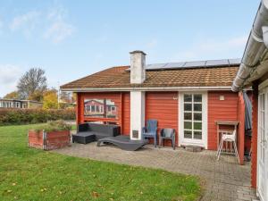 een rood huis met een patio in de tuin bij Holiday Home Baldo - 100m from the sea in SE Jutland by Interhome in Broager