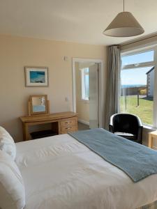 um quarto com uma cama, uma secretária e uma janela em Martyrs Bay Rooms em Iona