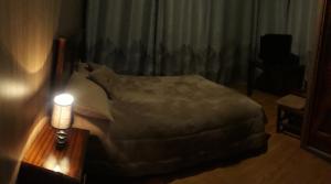 um quarto com uma cama e um candeeiro sobre uma mesa em EL TRAPICHE em Sigchos