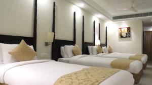 a row of four beds in a hotel room at Hotel Rajadhani in Trivandrum