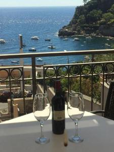 DHOME Baia Mazzaro' في تاورمينا: زجاجة من النبيذ موضوعة على طاولة مع كأسين من النبيذ