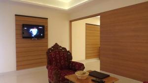 a living room with a chair and a tv at Hotel Rajadhani in Trivandrum