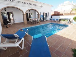 eine Villa mit einem Pool, Stühlen und einem Tisch in der Unterkunft Nerja Paradise Rentals - Villa Las Dalias in Nerja