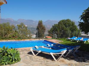 Nerja Paradise Rentals - Villa Los Girasoles في نيرخا: مسبح يوجد بجانبه كرسيين جلوس