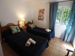 Nerja Paradise Rentals - Villa Los Girasoles في نيرخا: غرفة نوم بسريرين ونافذة ذات ستائر زرقاء