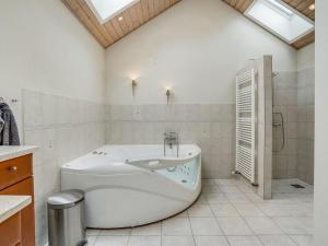 ein weißes Bad mit einer Badewanne und einer Dusche in der Unterkunft Holiday Home Birita - 20km from the sea in Western Jutland by Interhome in Ribe