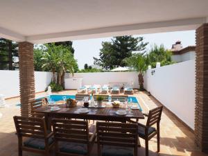 een patio met een tafel en stoelen en een zwembad bij Nerja Paradise Rentals - Villa Los Leones in Nerja