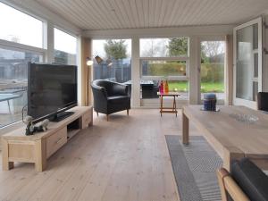 a living room with a television and a table at Holiday Home Mena - 200m from the sea by Interhome in Børkop +19 photos
