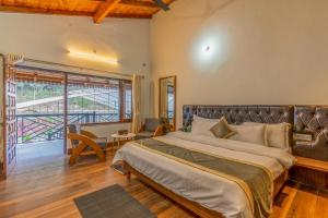 1 dormitorio con 1 cama grande y balcón en SaffronStays Kurmavana, Bhimtal - luxury cottage with pool and lawn - All clear roads, en Bhimtal