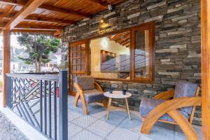 a patio with chairs and a table on a stone wall at SaffronStays Kurmavana, Bhimtal - luxury cottage with pool and lawn - All clear roads in Bhīm Tāl