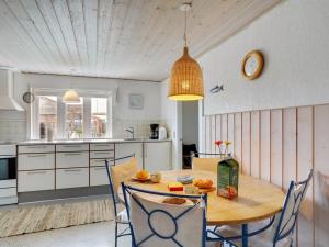 een keuken met een tafel met stoelen en een klok bij Holiday Home Fransiska - from the sea in Western Jutland by Interhome in Ulfborg