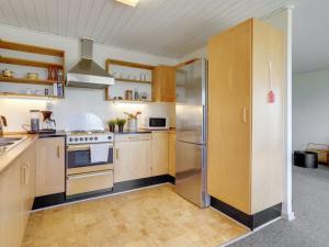 La cuisine est équipée d'armoires en bois et d'un réfrigérateur en acier inoxydable. dans l'établissement Holiday Home Launo - 150m to the inlet in SE Jutland by Interhome, à Børkop