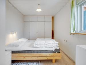 Schlafzimmer mit einem Bett mit weißer Bettwäsche und einem Fenster in der Unterkunft Holiday Home Launo - 150m to the inlet in SE Jutland by Interhome in Børkop