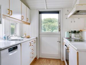 una cocina con armarios blancos y una ventana y una puerta en Holiday Home Algot - 100m to the inlet in SE Jutland by Interhome, en Børkop