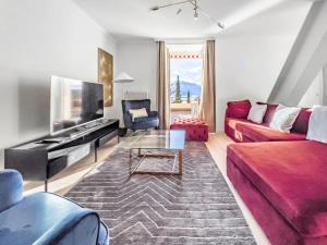 a living room with a red couch and a table at Chic 2 bedroom apartment near Chillion castle in Veytaux