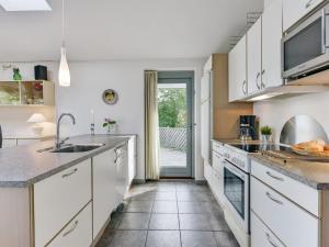 a kitchen with white cabinets and tile flooring at Holiday Home Freding - 250m to the inlet by Interhome in Børkop