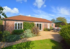 a brick house with a patio and a yard at Oak Lodge in Alderford