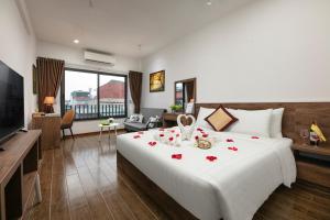 a bedroom with a large white bed with roses on it at Hanoi Saga Hotel in Hanoi