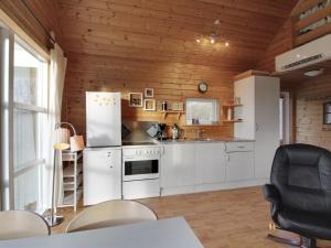 a kitchen with white appliances and wooden walls at Holiday Home Terese - 45km from the sea in Western Jutland by Interhome in Grindsted