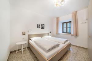 ein weißes Schlafzimmer mit einem Bett und einem Tisch in der Unterkunft Domus Faber 2a in Meran