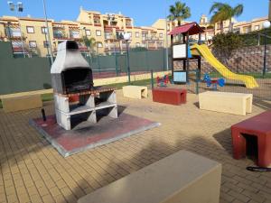 a playground with a grill and a slide at Apartamento Costa Esuri in Ayamonte