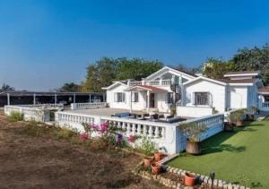 a white house with a fence and a yard at SaffronStays Brunton House, Alibaug - luxury pool villa near Awas Beach in Alibaug